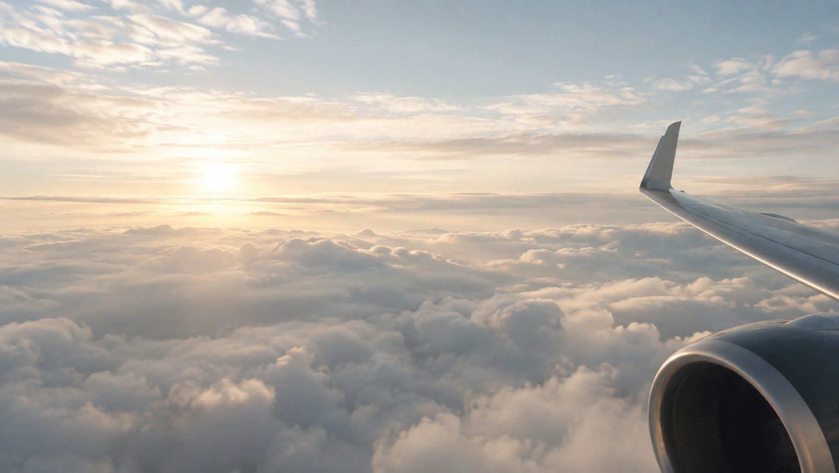 Wing and engine above a sea of clouds at sunrise